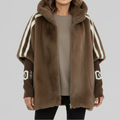 Woman wearing an oversized hooded zip-up jacket with white sporty stripes on the sleeves and ribbed cuffs, styled over a neutral top and black pants._0