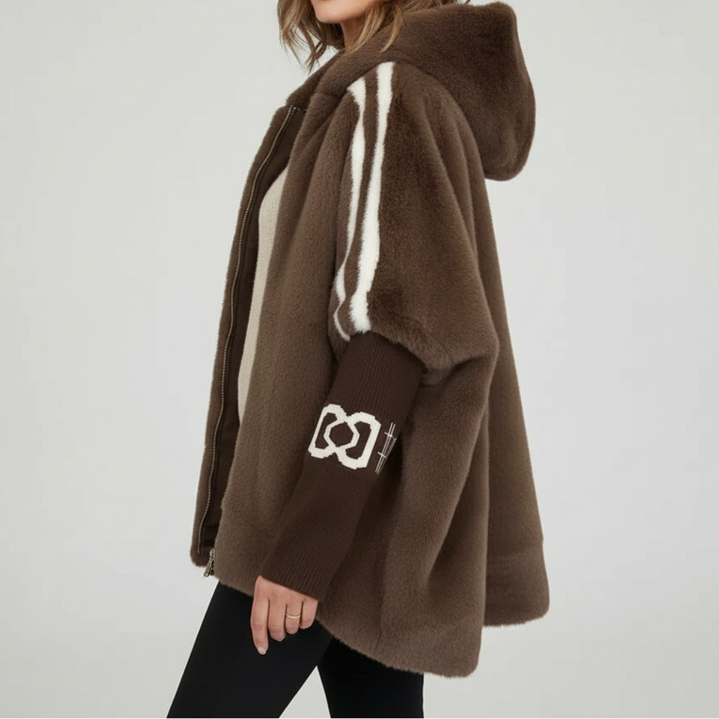 Woman wearing an oversized hooded zip-up jacket with white sporty stripes on the sleeves and ribbed cuffs, styled over a neutral top and black pants._1
