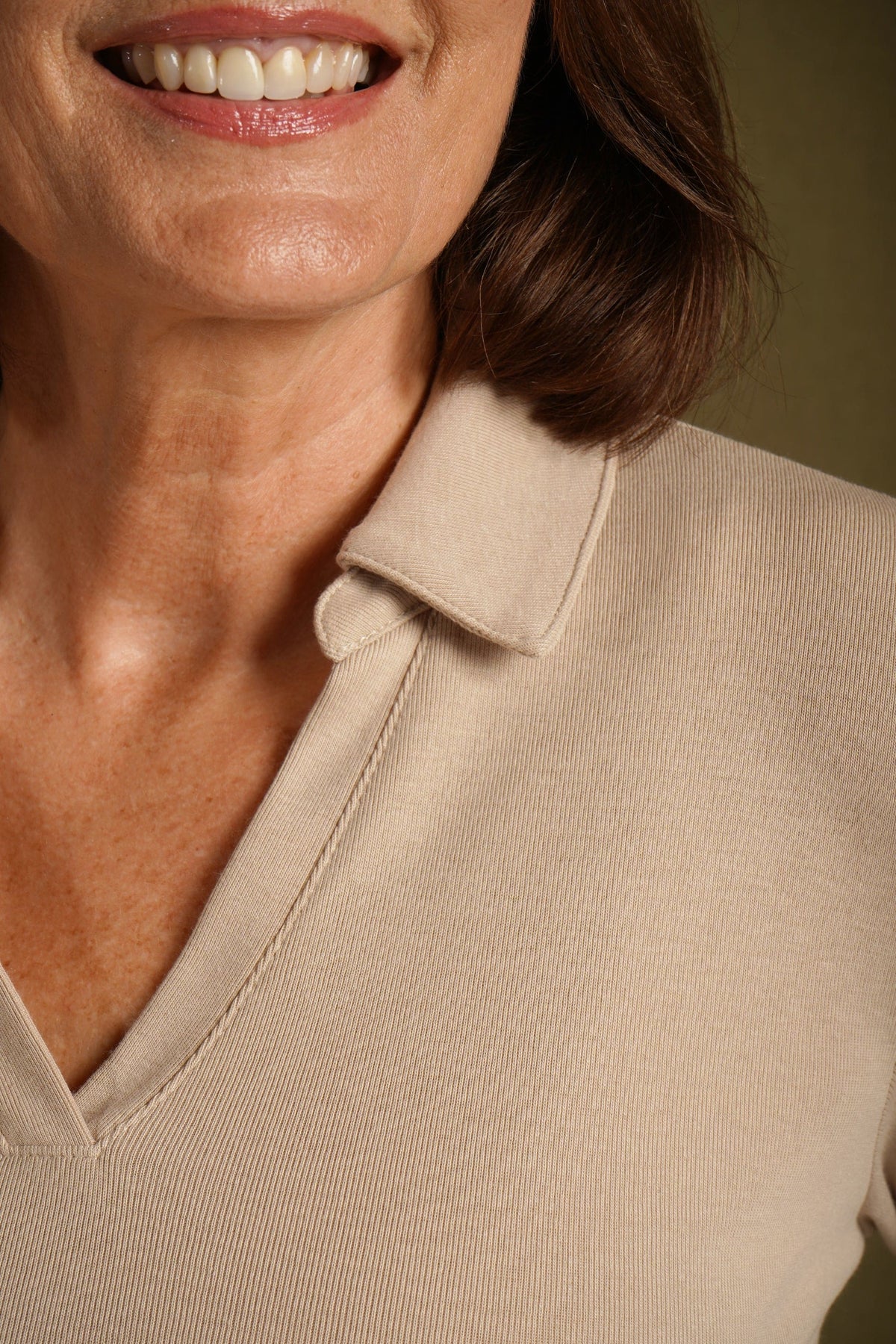 Woman wearing a beige long sleeve top with a point collar and open V-neckline, paired with a blue and white printed skirt._3