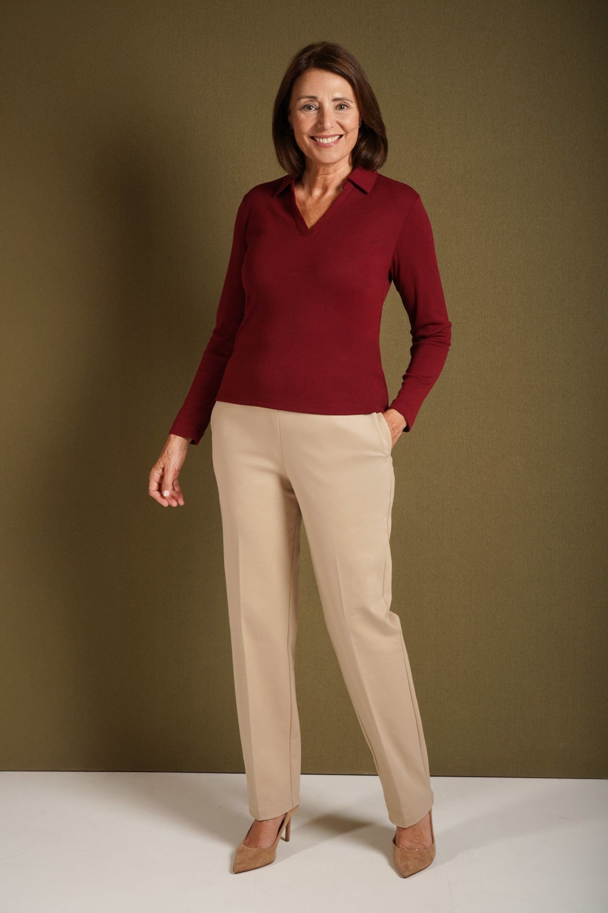 Woman wearing a beige long sleeve top with a point collar and open V-neckline, paired with a blue and white printed skirt._4