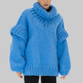 Woman wearing an oversized bright blue chunky knit turtleneck sweater with long sleeves and black trousers._0