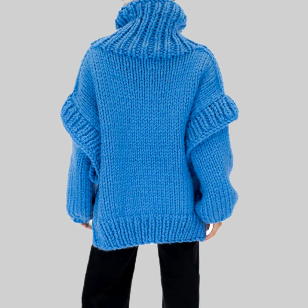Woman wearing an oversized bright blue chunky knit turtleneck sweater with long sleeves and black trousers._5