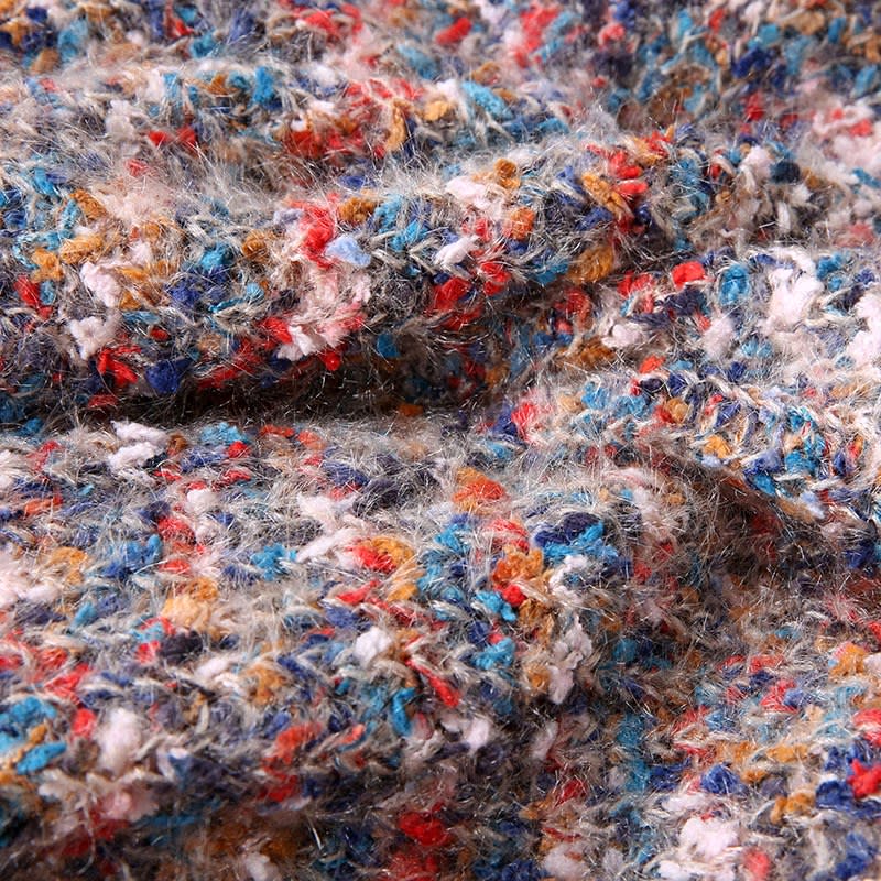 Oversized v-neck sweater on a black hanger, knitted in a speckled multicolor yarn of pink, blue, yellow and cream on a cream base, with long blouson sleeves and ribbed cuffs and hem._3