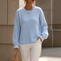 Woman wearing a light blue ribbed knit crew neck sweater with white trim at the cuffs and hem, paired with white trousers._0