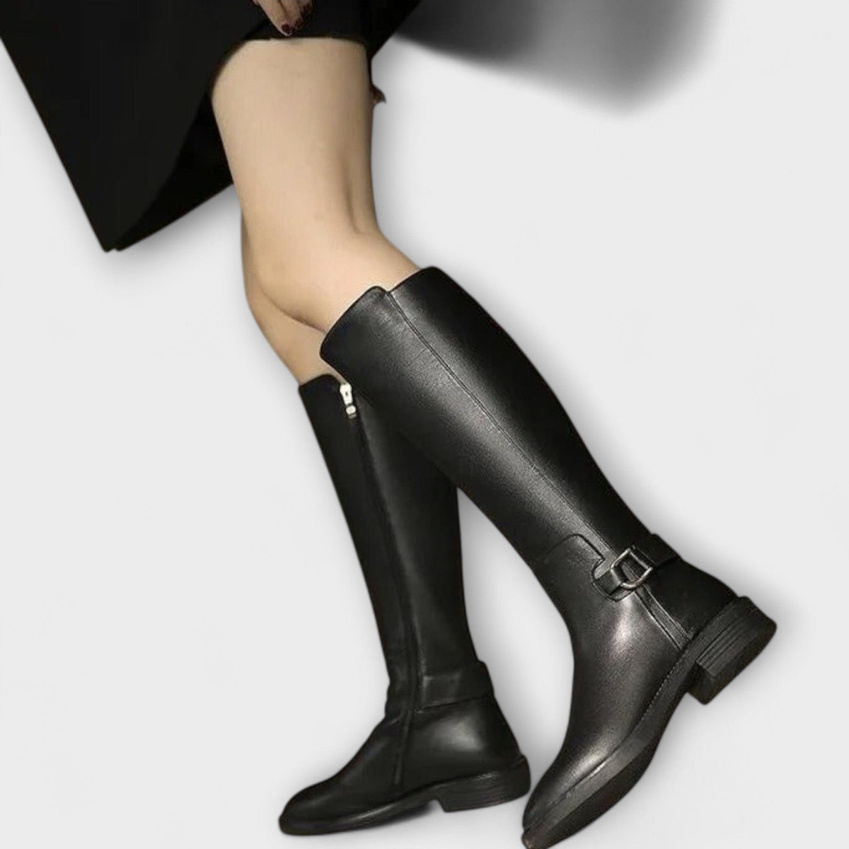 Model wearing knee high boots with a block heel and buckle detail, styled with a pleated skirt._1
