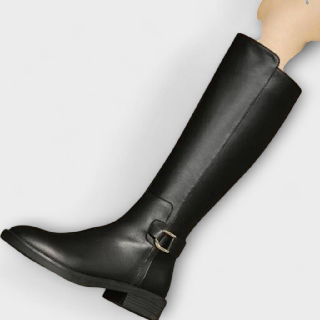 Model wearing knee high boots with a block heel and buckle detail, styled with a pleated skirt._3