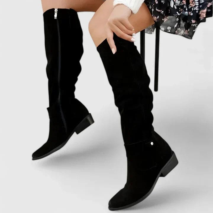 Woman wearing knee-high slouchy boots with a block heel and side zipper detail, styled outdoors on pavement._5