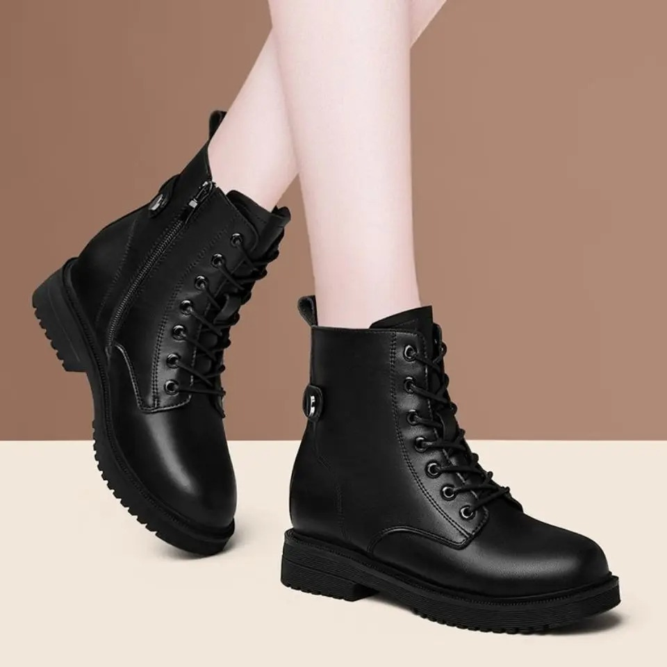 Black lace-up ankle boots standing on a light surface, showing the front lacing, rounded toes, low heels, and deep textured tread.