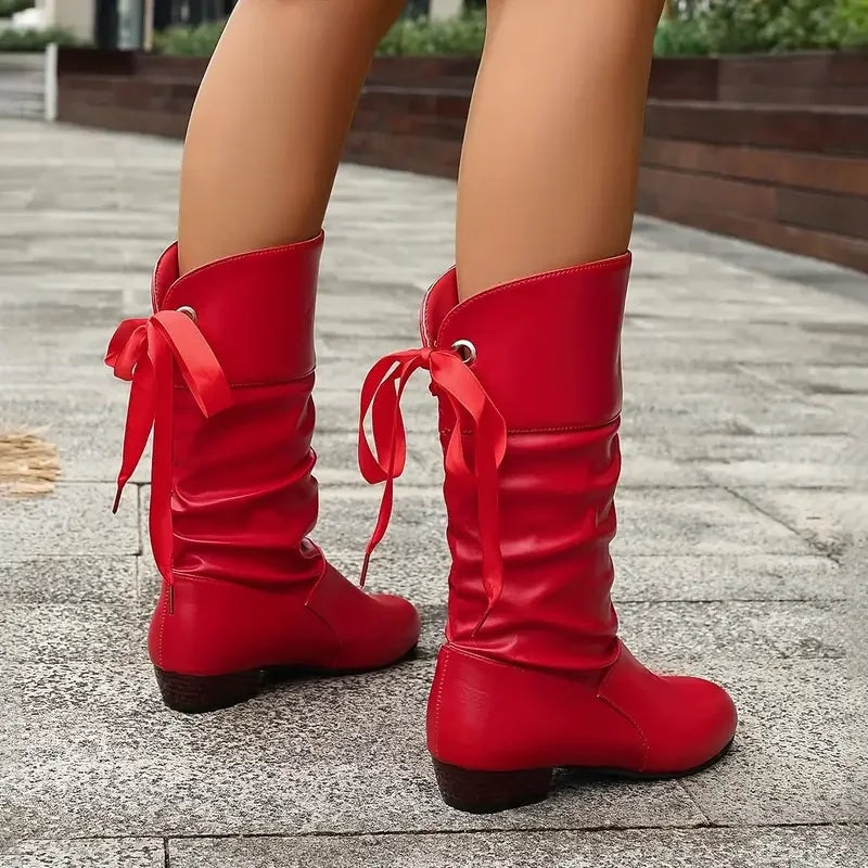 Rear three-quarter view of red slouch calf boots showing the lace-up ties and gathered shafts.