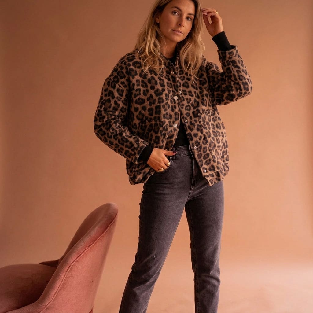 Woman wearing a leopard print bomber jacket with ribbed cuffs and snap button closures against a neutral background._3