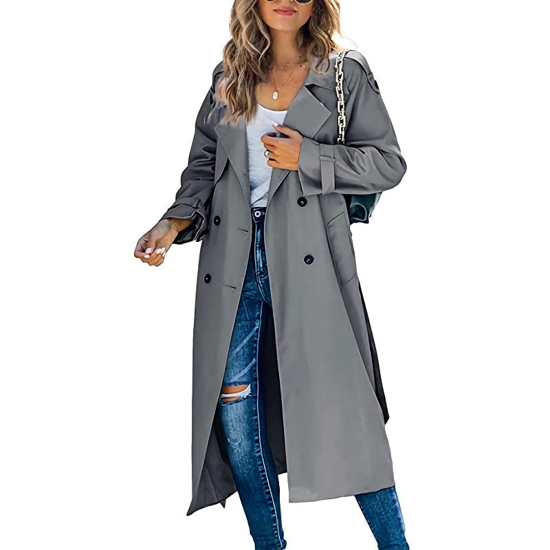 Charcoal gray long trench coat with black buttons, a double-breasted front, and belted sleeves styled over blue jeans.