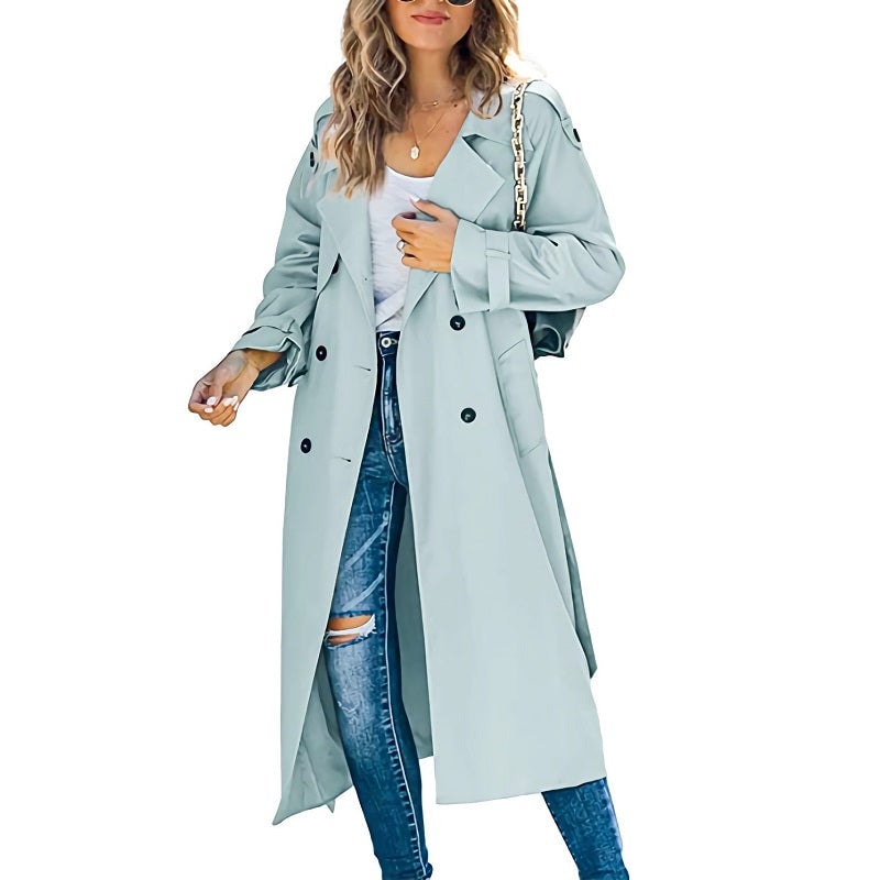 Pale blue long double-breasted trench coat layered over a light shirt and ripped jeans, with the open front creating a flowing silhouette.