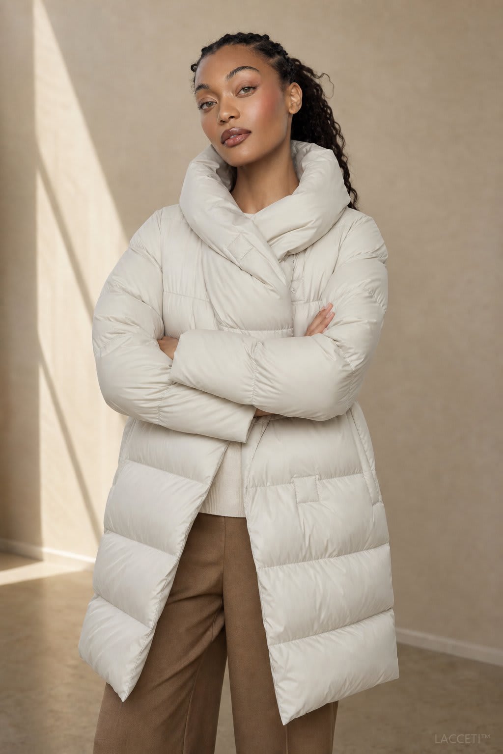 Model wearing a long black puffer parka with oversized fit and structured hood, styled with cream trousers and black ankle boots_5