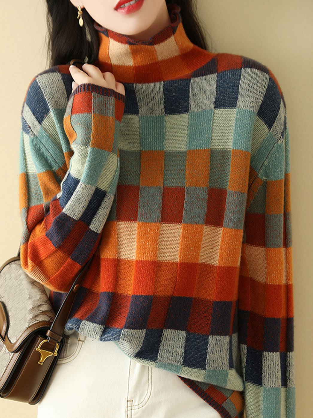 Woman wearing a loose fit turtleneck jumper with a colorblock plaid pattern in shades of orange, teal, navy, and grey._0