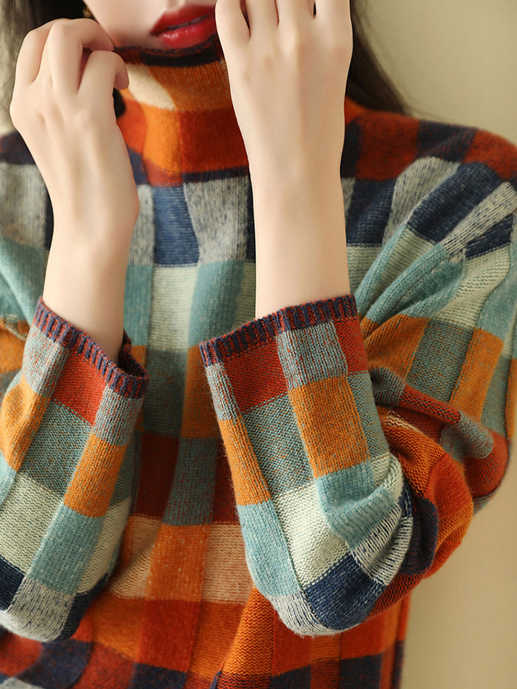 Woman wearing a loose fit turtleneck jumper with a colorblock plaid pattern in shades of orange, teal, navy, and grey._2
