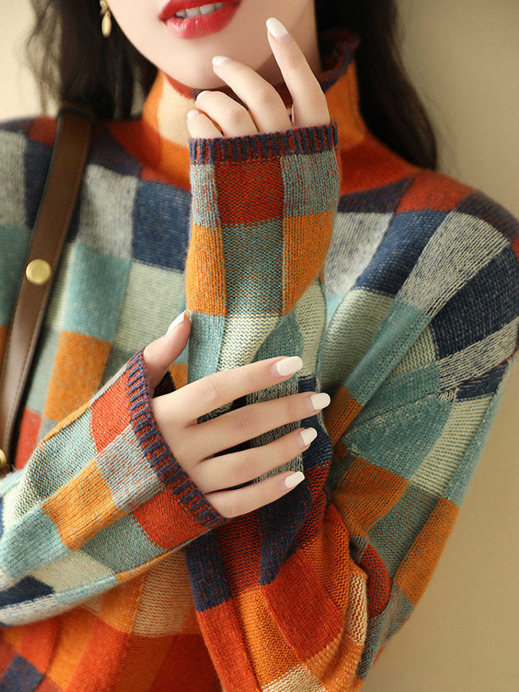 Woman wearing a loose fit turtleneck jumper with a colorblock plaid pattern in shades of orange, teal, navy, and grey._3