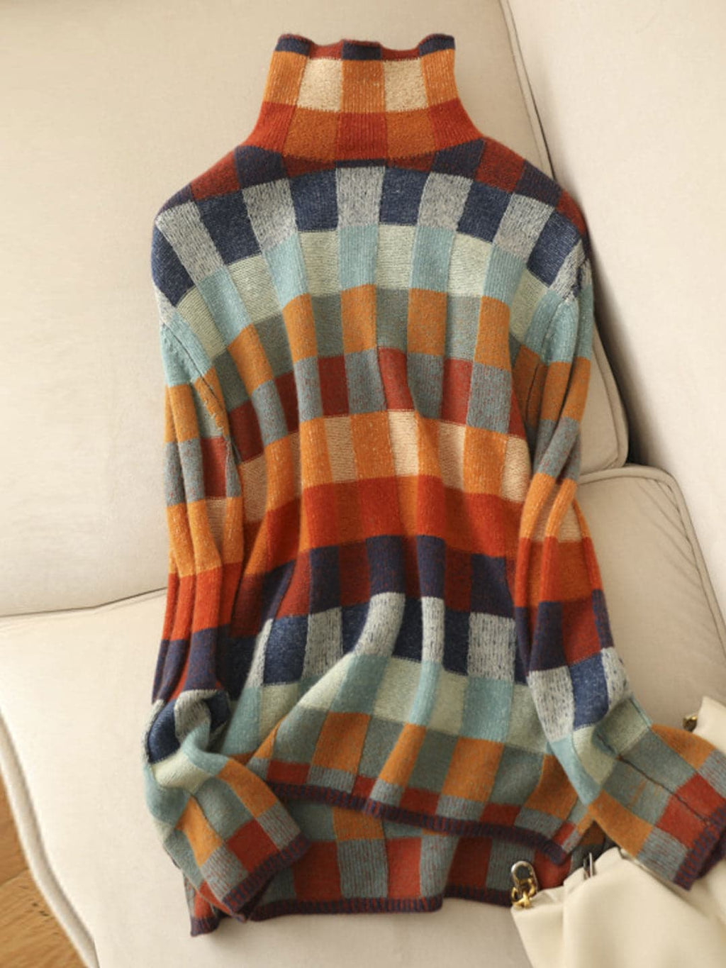 Woman wearing a loose fit turtleneck jumper with a colorblock plaid pattern in shades of orange, teal, navy, and grey._4