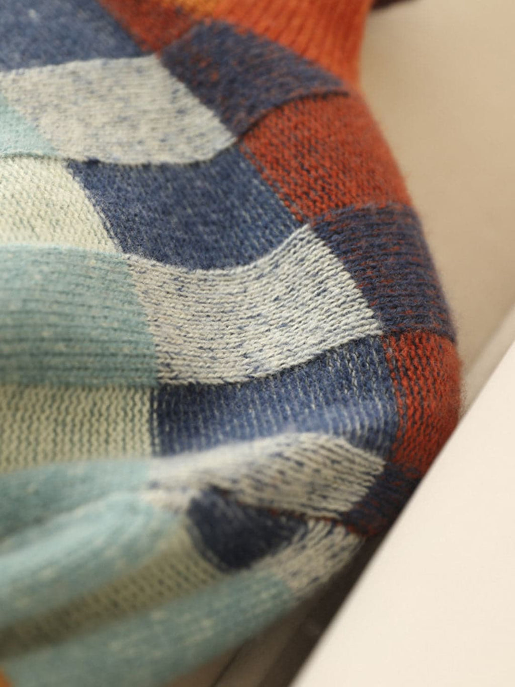 Woman wearing a loose fit turtleneck jumper with a colorblock plaid pattern in shades of orange, teal, navy, and grey._5