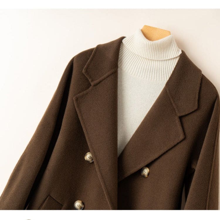A double breasted longline coat with notched lapels and side welt pockets displayed on a mannequin._4