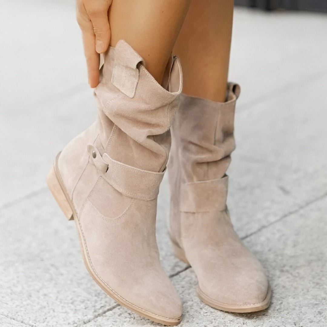 Light beige boots viewed from above, showing the front buckle straps, gathered shafts, rounded pointed toes, and side zipper.