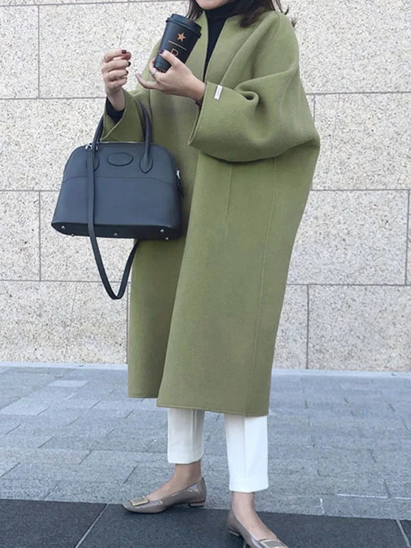 Three-quarter view of the olive green coat displaying its open front, longline shape, and softly folded bracelet sleeves.