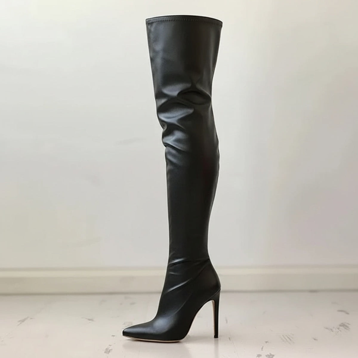 Single black over-the-knee boot shown in profile with a pointed toe, tall shaft, and slim stiletto heel.