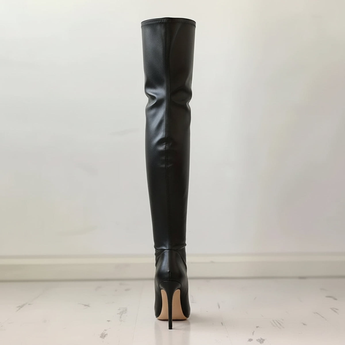 Rear view of a black over-the-knee boot highlighting the tall shaft, center seam, and narrow stiletto heel.