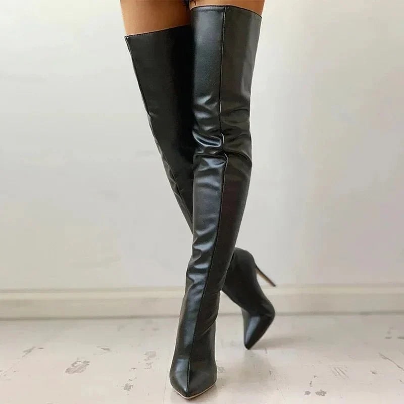 Front three-quarter view of black over-the-knee pointed-toe stiletto boots with one leg crossed behind the other.