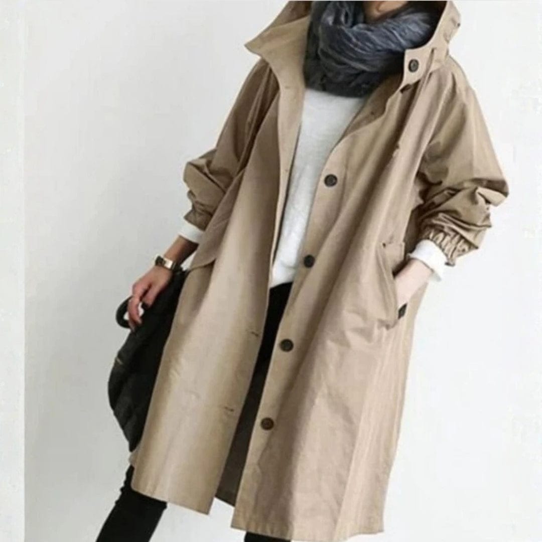 Woman wearing an oversized beige hooded trench coat with button front closure, layered over a white top and dark scarf._0