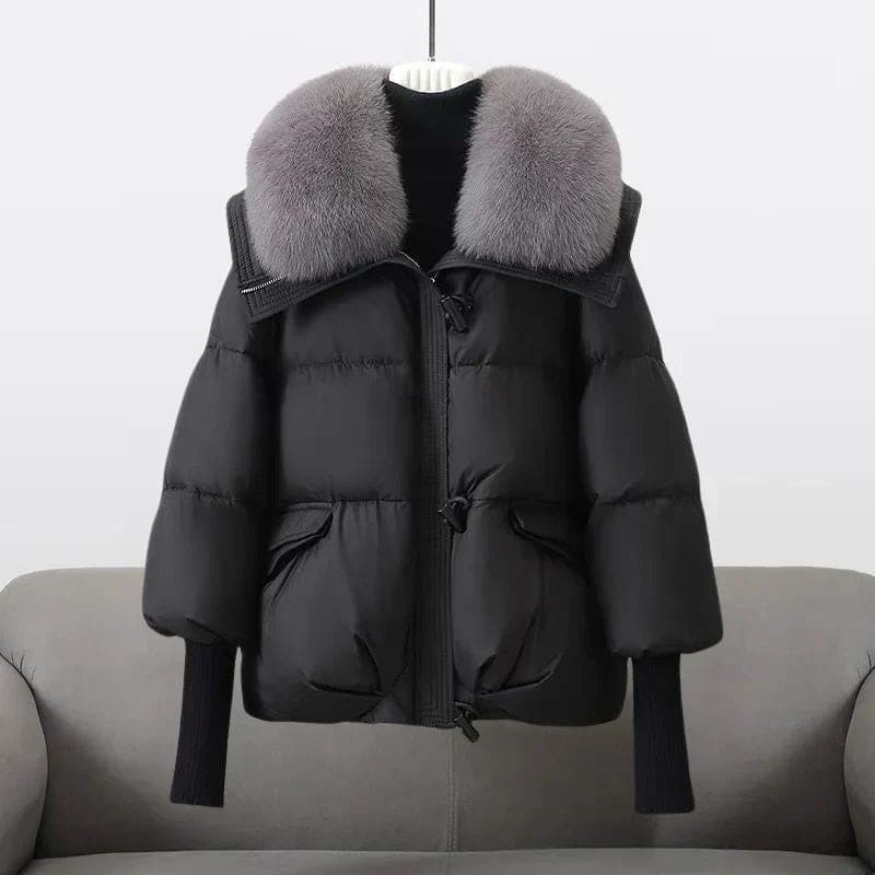 Woman wearing an oversized black puffer jacket with a wide statement collar, styled over a black turtleneck and pants._1
