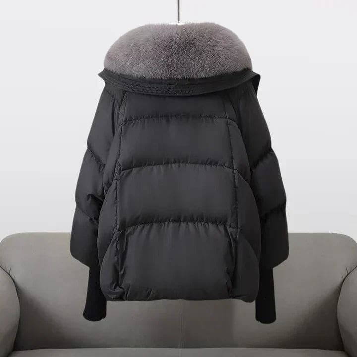 Woman wearing an oversized black puffer jacket with a wide statement collar, styled over a black turtleneck and pants._2