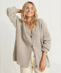 Light taupe oversized V-neck cardigan styled with rolled sleeves over a light top and cream trousers.