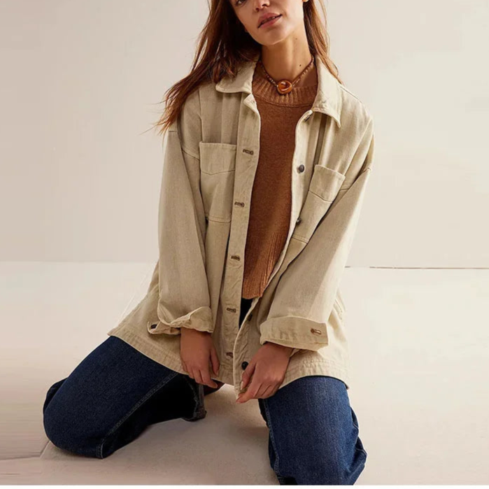 Woman wearing an oversized button-front jacket with chest pockets and a relaxed silhouette, styled over a white top and pants._25