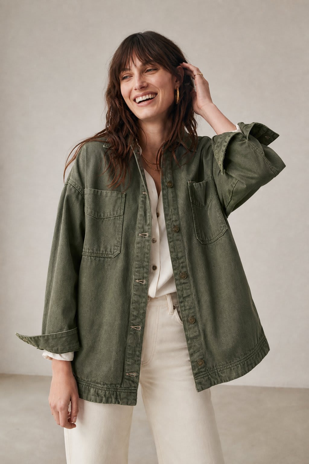Woman wearing an oversized button-front jacket with chest pockets and a relaxed silhouette, styled over a white top and pants._8