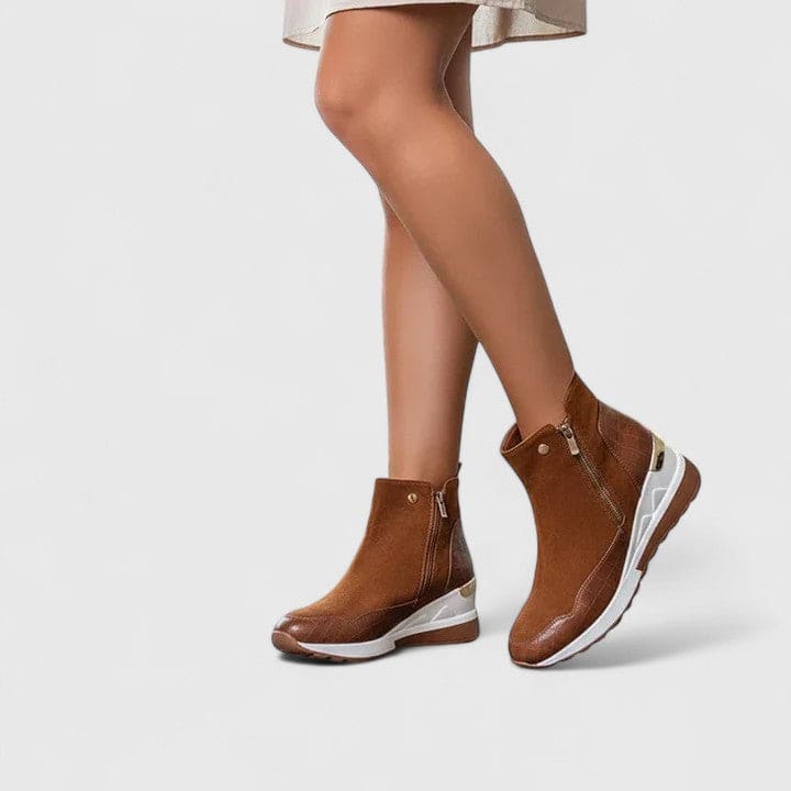 Woman wearing sporty platform ankle boots with textured panels, wedge sole, and side zipper closure._1