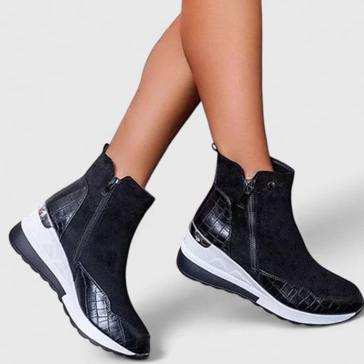 Woman wearing sporty platform ankle boots with textured panels, wedge sole, and side zipper closure._4
