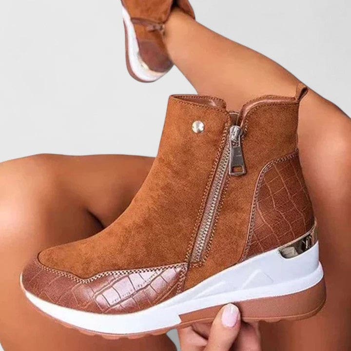 Woman wearing sporty platform ankle boots with textured panels, wedge sole, and side zipper closure._6
