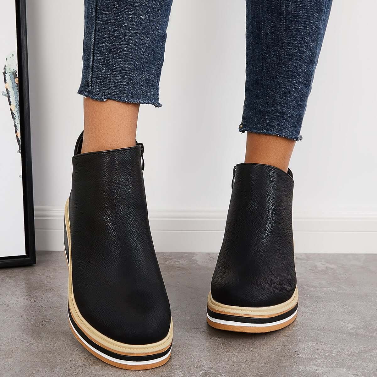 Black ankle boots shown from the front with rounded toes and layered platform soles, styled with cropped jeans.