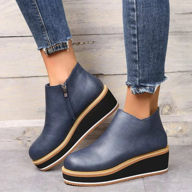 Navy blue platform ankle boots shown at a three-quarter angle with cropped jeans and visible side zipper.