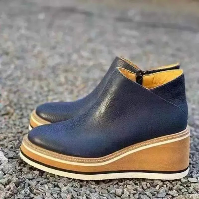 Navy blue platform ankle boots displayed outdoors on gravel, highlighting their clean ankle-height silhouette.