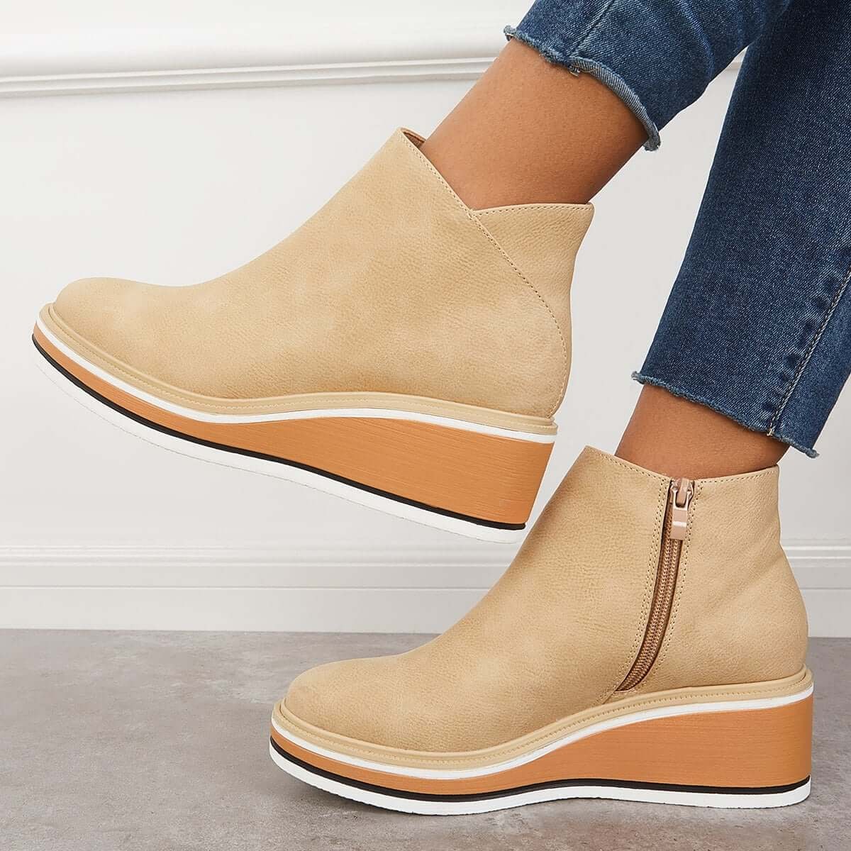 Light beige platform ankle boots in side view, with one boot lifted and the side zipper visible.
