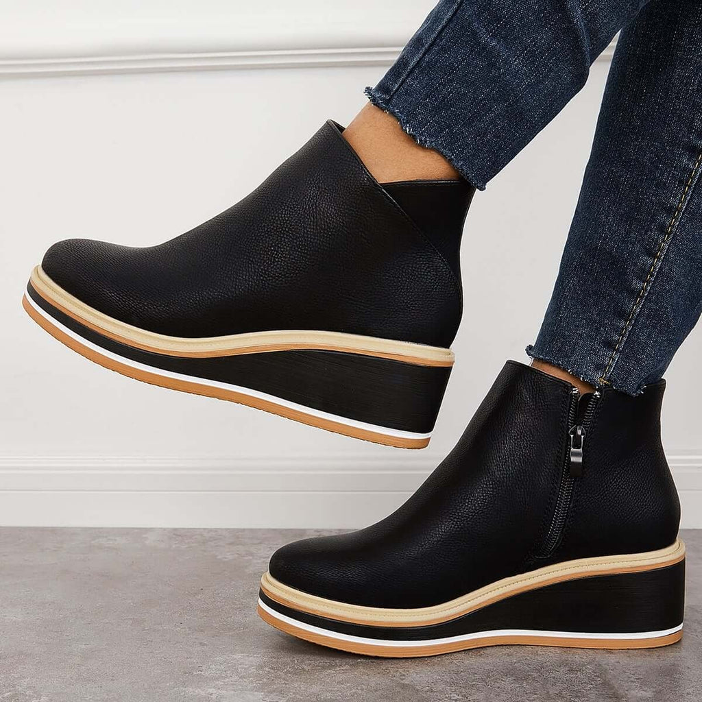 Black platform ankle boots in side view, showing the raised wedge-like sole and side zipper.