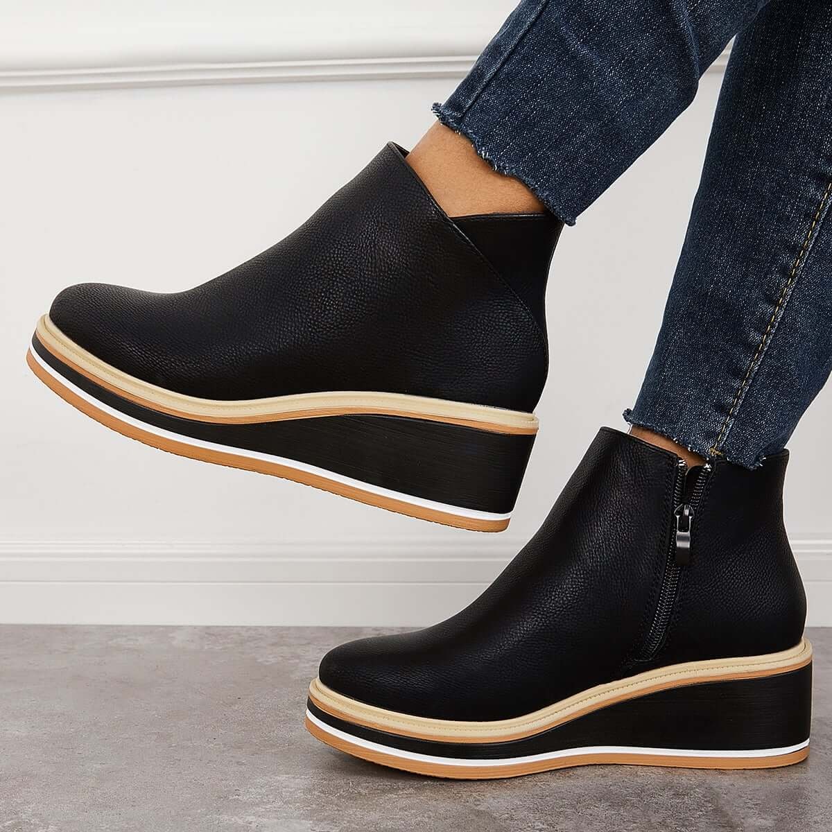 Black platform ankle boots in side view, showing the raised wedge-like sole and side zipper.