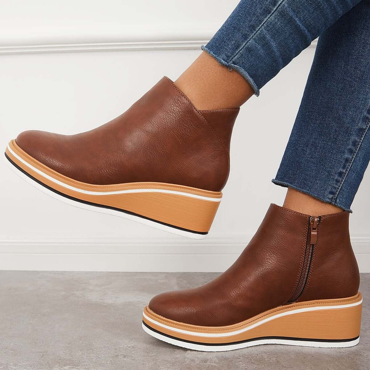 Brown platform ankle boots in side view, showing the side zipper and raised wedge sole.