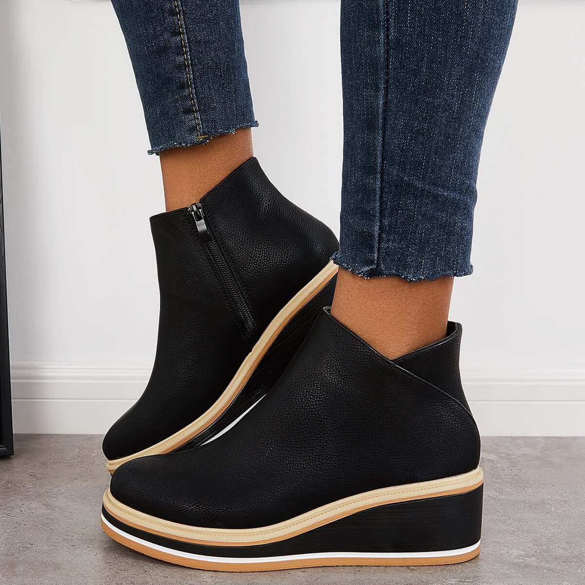 Black platform ankle boots viewed from the side while worn, highlighting the ankle height and layered sole.