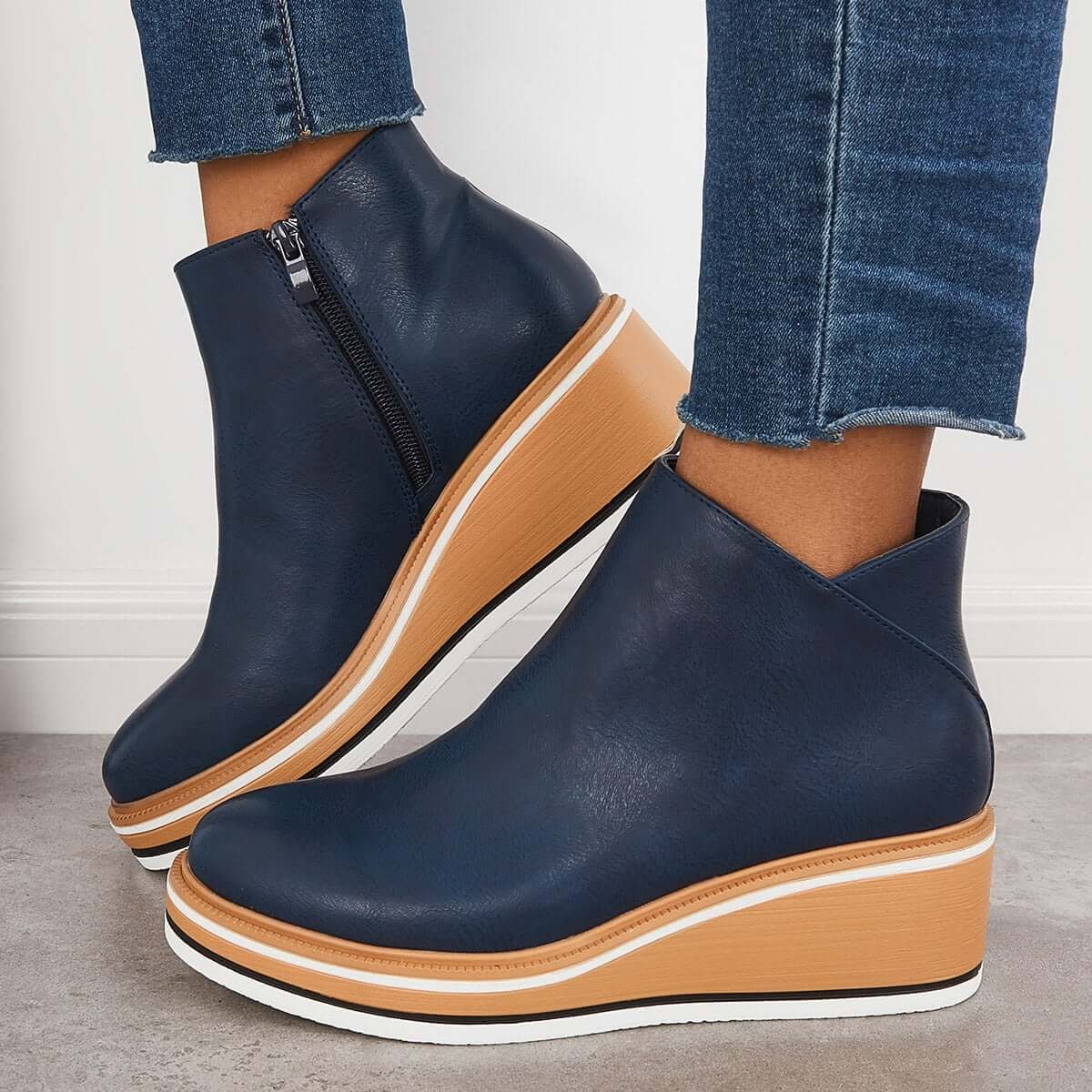 Navy blue platform ankle boots worn with cropped jeans, shown from the side to emphasize the raised sole.