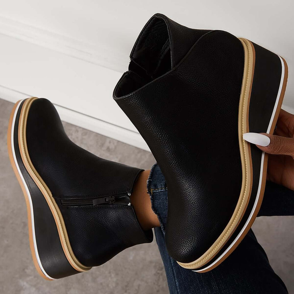 Black ankle boot held above another boot to highlight the side zipper, ankle opening, and layered platform sole.