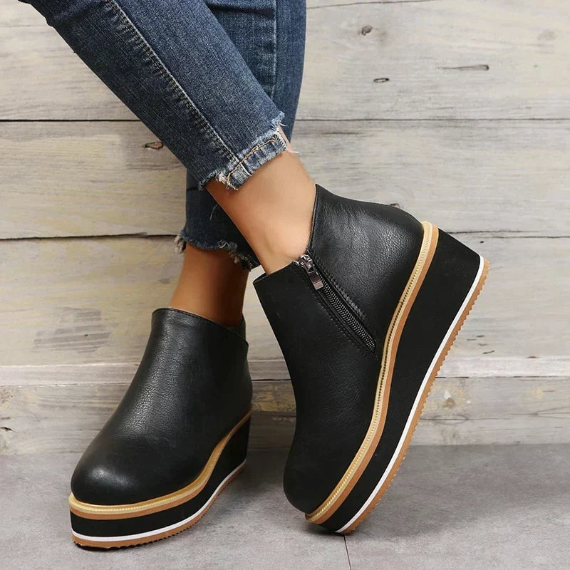 Black ankle boots crossed at the ankles, highlighting the side zipper and tall platform profile.