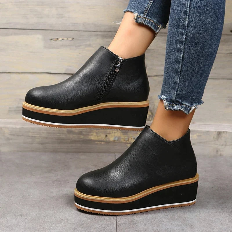 Black platform ankle boots shown in a clean side view with rounded toes and contrasting layered soles.