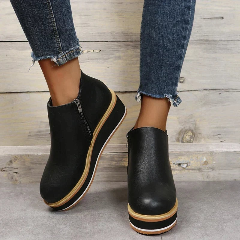 Black ankle boots viewed from the front and side, showing the smooth ankle shaft and raised platform construction.